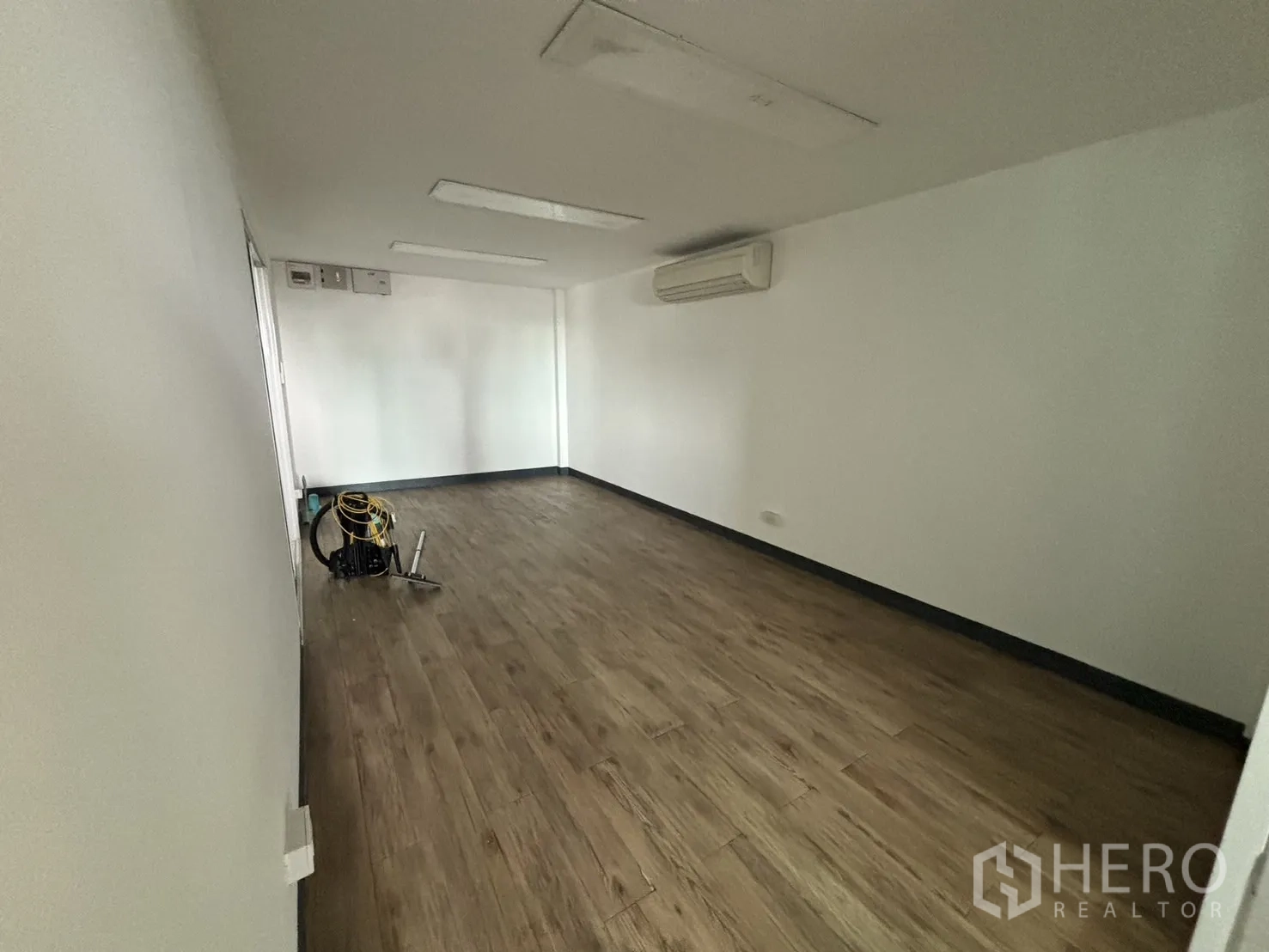Office Space for rent in Watthana, Bangkok - Compact meeting room with wood floors, white walls and a wall-mounted AC.