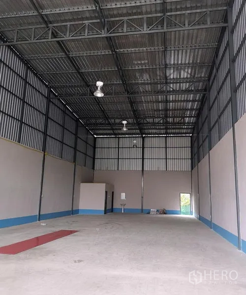 Warehouse for rent in Prawet, Bangkok - Open warehouse floor with high roof, a small service room and a wash basin at the rear.
