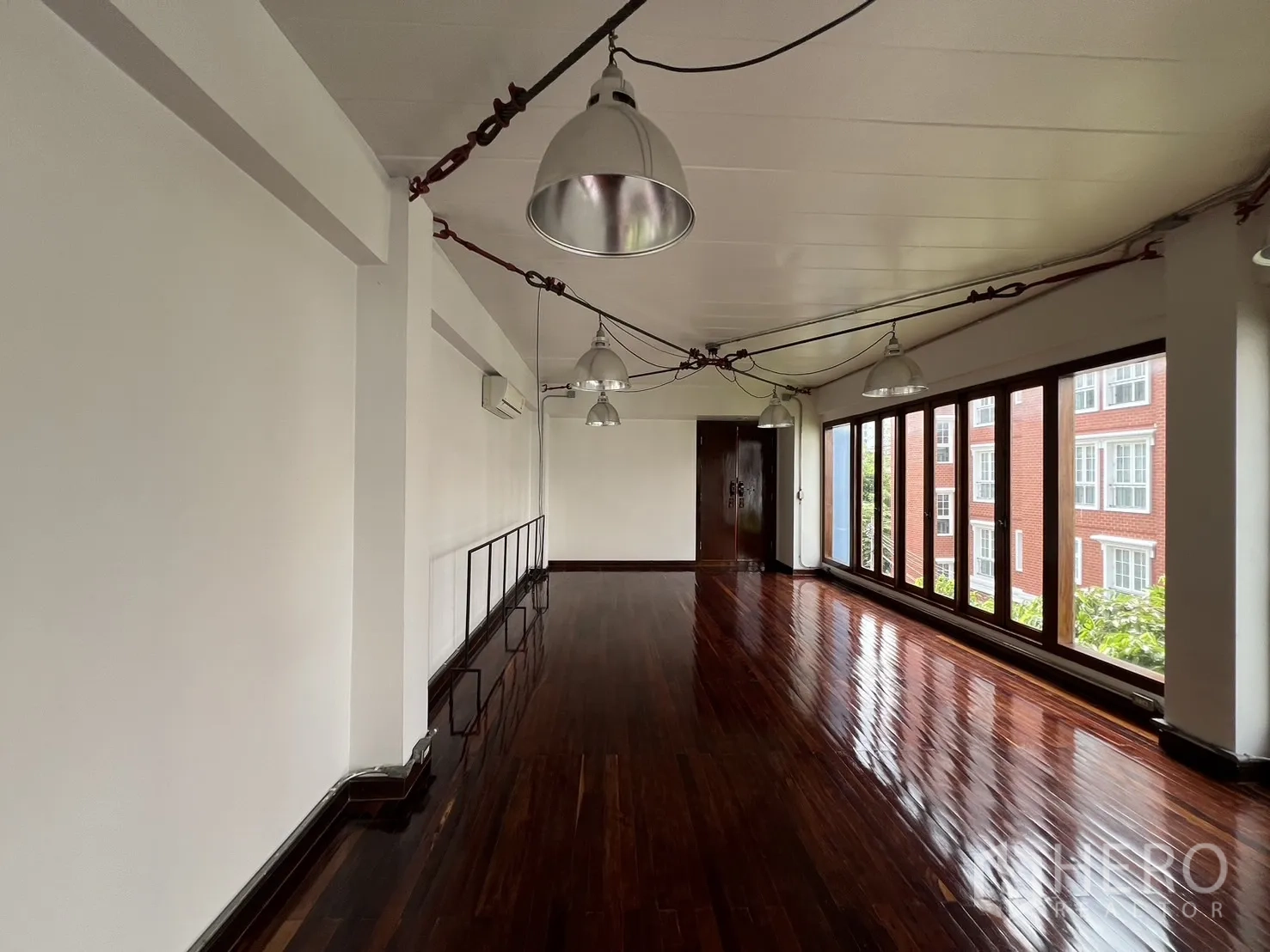 Home Office for rent in Watthana, Bangkok - Long corridor-style workspace with glossy timber floor, a wall of windows and city view.