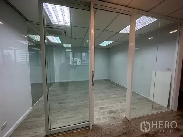 Office Space for rent in Din Daeng, Bangkok - Glass-partitioned meeting room with sliding door, wood floors and grid ceiling lights.