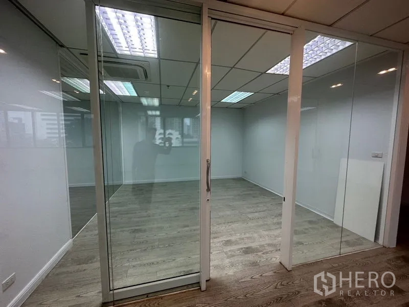 Office Space for rent in Din Daeng, Bangkok - Glass-partitioned meeting room with sliding door, wood floors and grid ceiling lights.