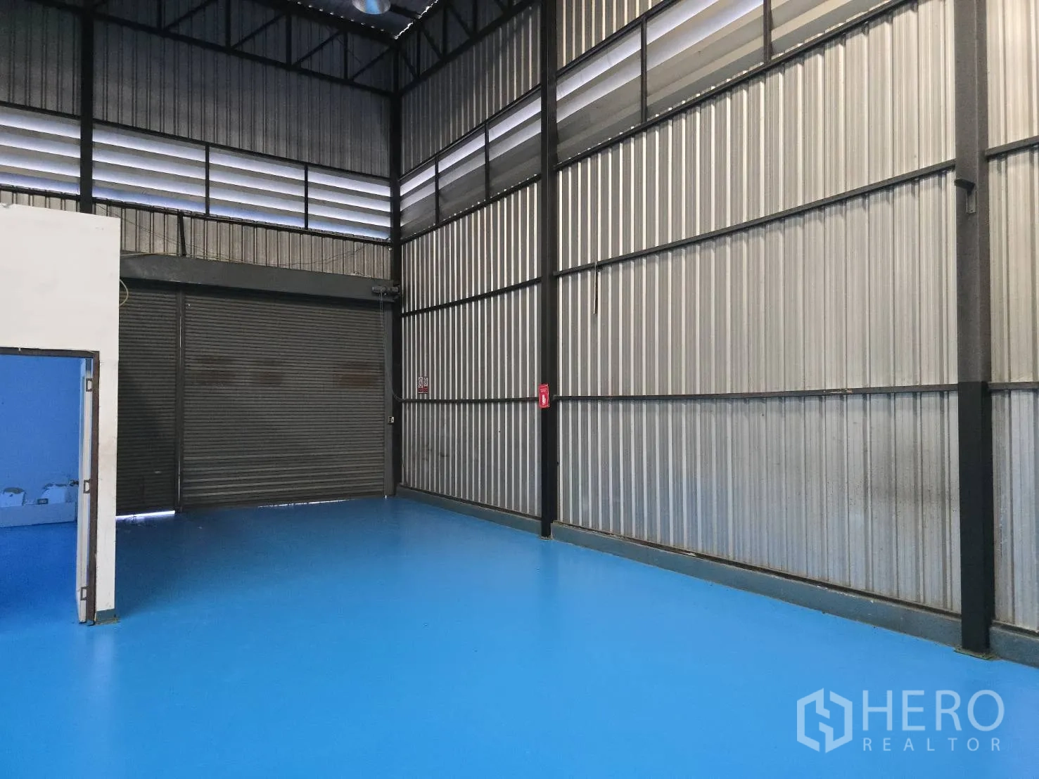 Warehouse for rent in Bang Phli, Samut Prakan - Large roller shutter door and high metal walls inside the warehouse.