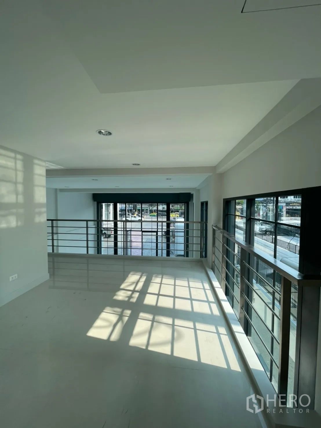 Home Office for rent in Suan Luang, Bangkok - Mezzanine level with metal railing overlooking large windows and a bright workspace.