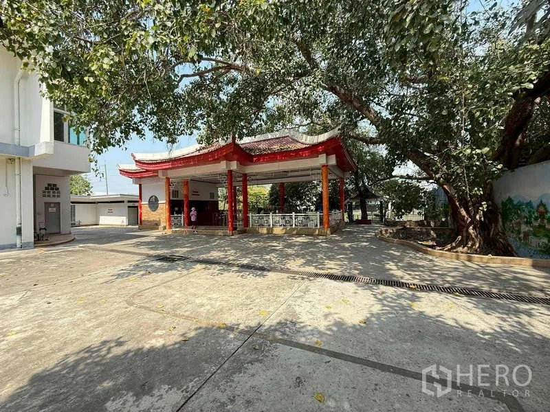 Warehouse for rent in Mueang Samut Prakan, Samut Prakan - Shaded courtyard featuring a red-roof pavilion beneath a large tree.