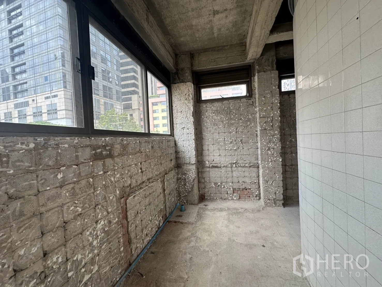 Retail Space for rent in Bang Rak, Bangkok - Service corridor with raw brick walls and windows looking toward city office towers.