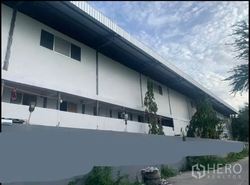 货栈 出租在Sai Noi, Nonthaburi - 仓库侧立面，长条建筑与有顶走道和窗户