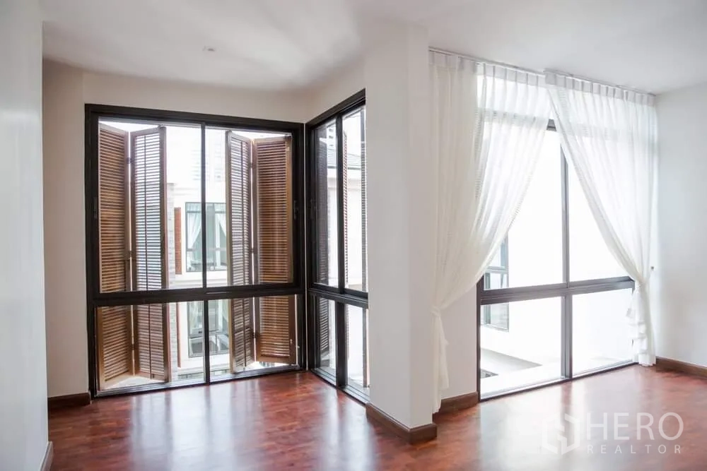 独立式住宅 出租在Khlong Toei, Bangkok - 明亮转角空间，白色窗帘与木质折叠百叶窗。