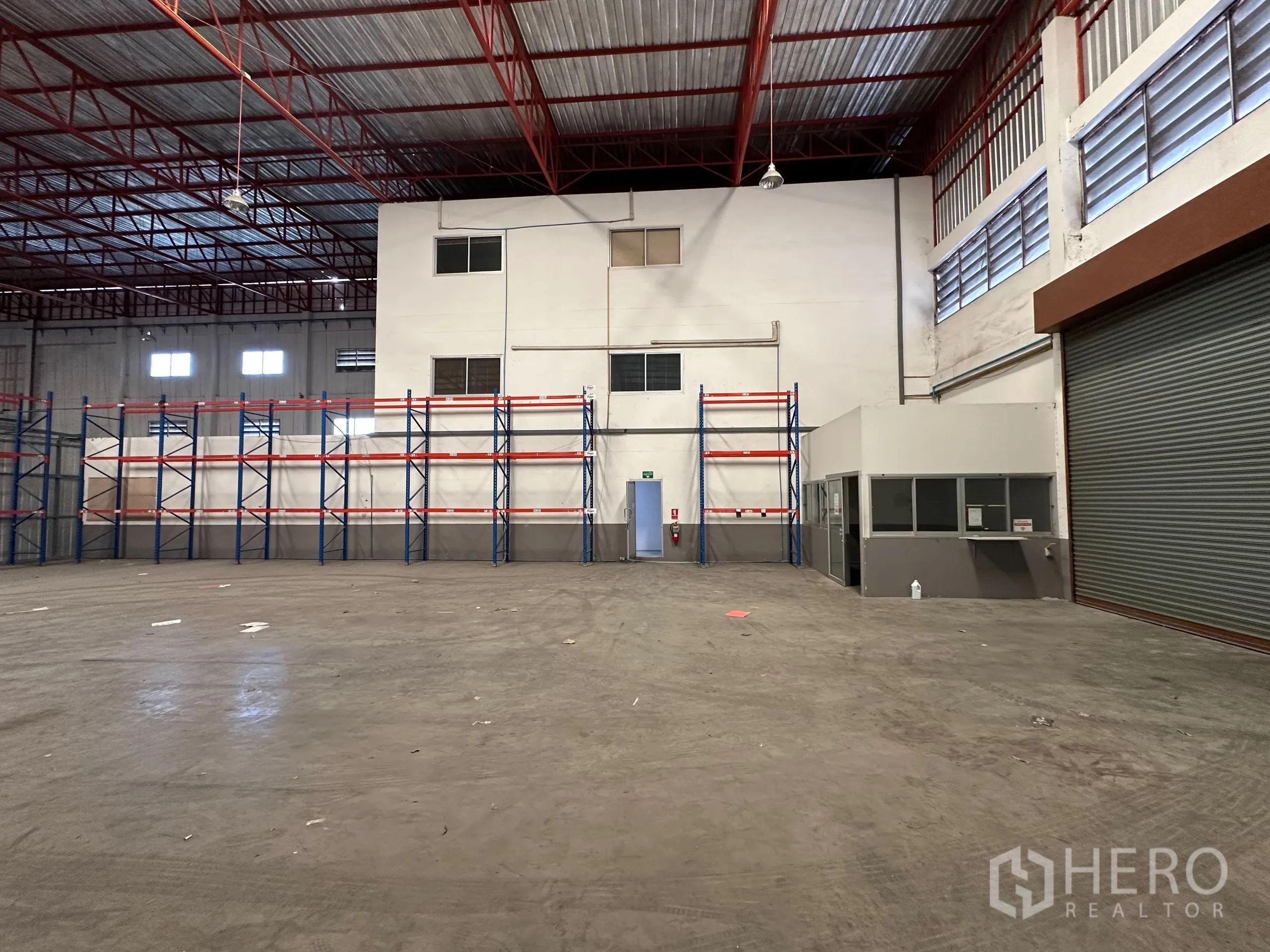 Factory for rent - Warehouse interior with storage racks and small office by the loading door.