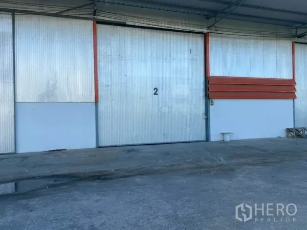 Warehouse for rent in Mueang Pathum Thani, Pathum Thani - Large metal sliding door numbered 2 at the covered loading bay of the warehouse with a concrete apron.