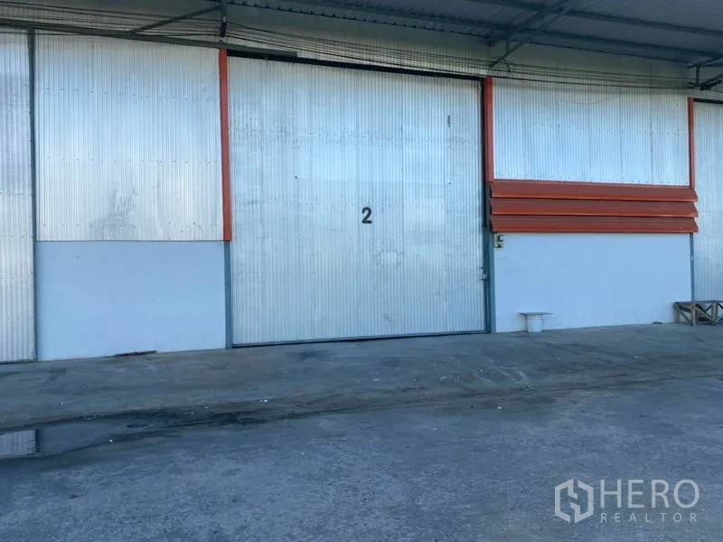 Warehouse for rent in Mueang Pathum Thani, Pathum Thani - Large metal sliding door numbered 2 at the covered loading bay of the warehouse with a concrete apron.