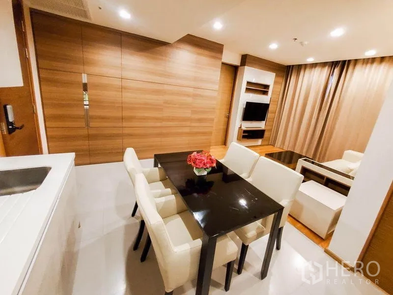 Condominium for rent in Bang Rak, Bangkok - Open-plan dining and living area with wood feature wall, recessed lighting, and built-in TV unit.