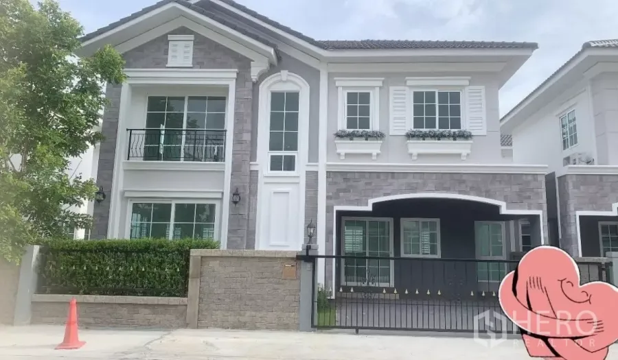 Detached House for rent in Prawet, Bangkok - Two-storey detached house in Prawet with grey brick facade, white trim, balcony and gated driveway.