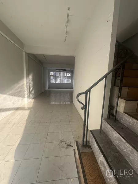 Shophouse for rent in Khlong Toei, Bangkok - Hallway with staircase leading to upper levels and open retail space ahead.