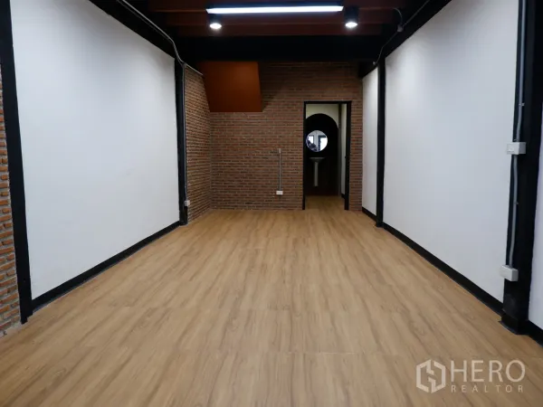 Home Office for sale in Bang Rak, Bangkok - Open-plan office floor with wood-look flooring, exposed brick accent walls, ceiling beams and downlights.