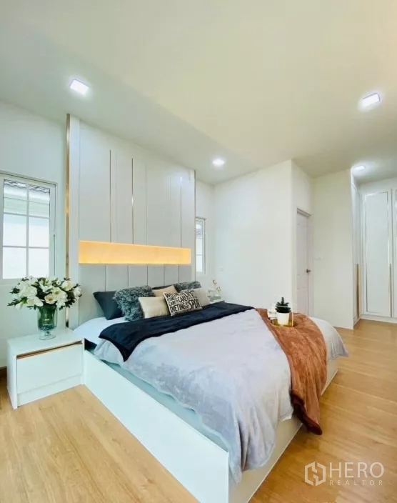 Detached House for rent in Prawet, Bangkok - Spacious bedroom angle showing fitted wardrobe, wood floors and crisp white walls.