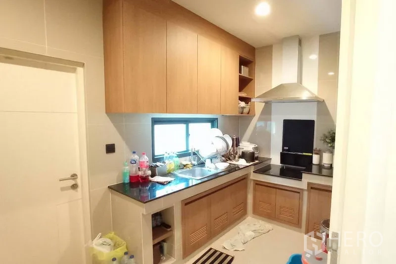 Detached House for rent in Bang Kapi, Bangkok - Fitted kitchen with wood cabinetry, stone countertop, electric hob and range hood.