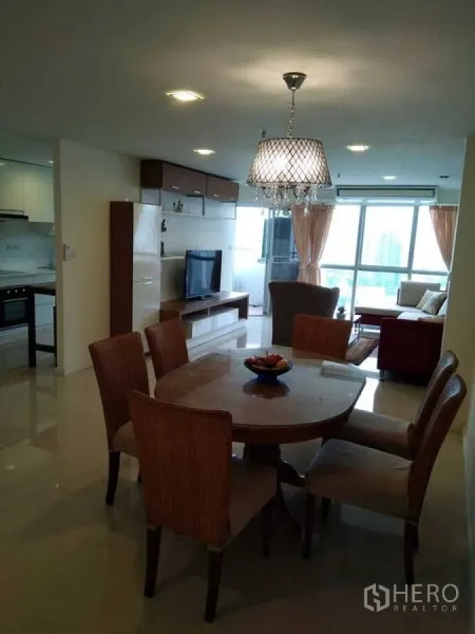 Condominium for rent in Khlong Toei, Bangkok - Dining area with round table and pendant chandelier adjoining the living room with TV.