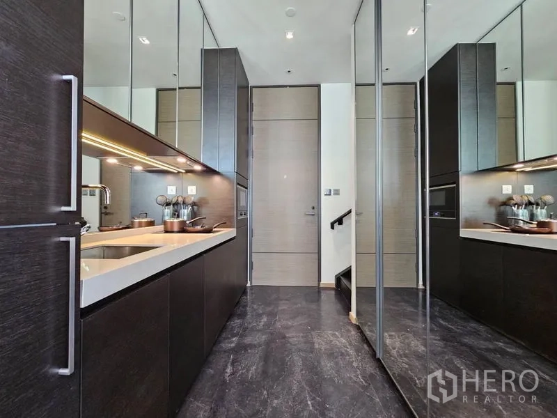 Condominium for rent - Sleek galley kitchen with mirrored cabinets, under-cabinet lighting, and sink.