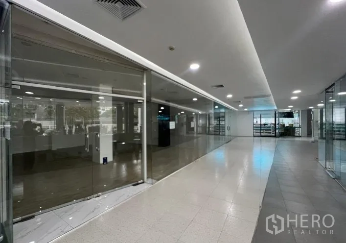 Retail Space for rent - Bright corridor of a retail mall with glass-walled shopfronts and recessed ceiling lights near BTS Phra Khanong.