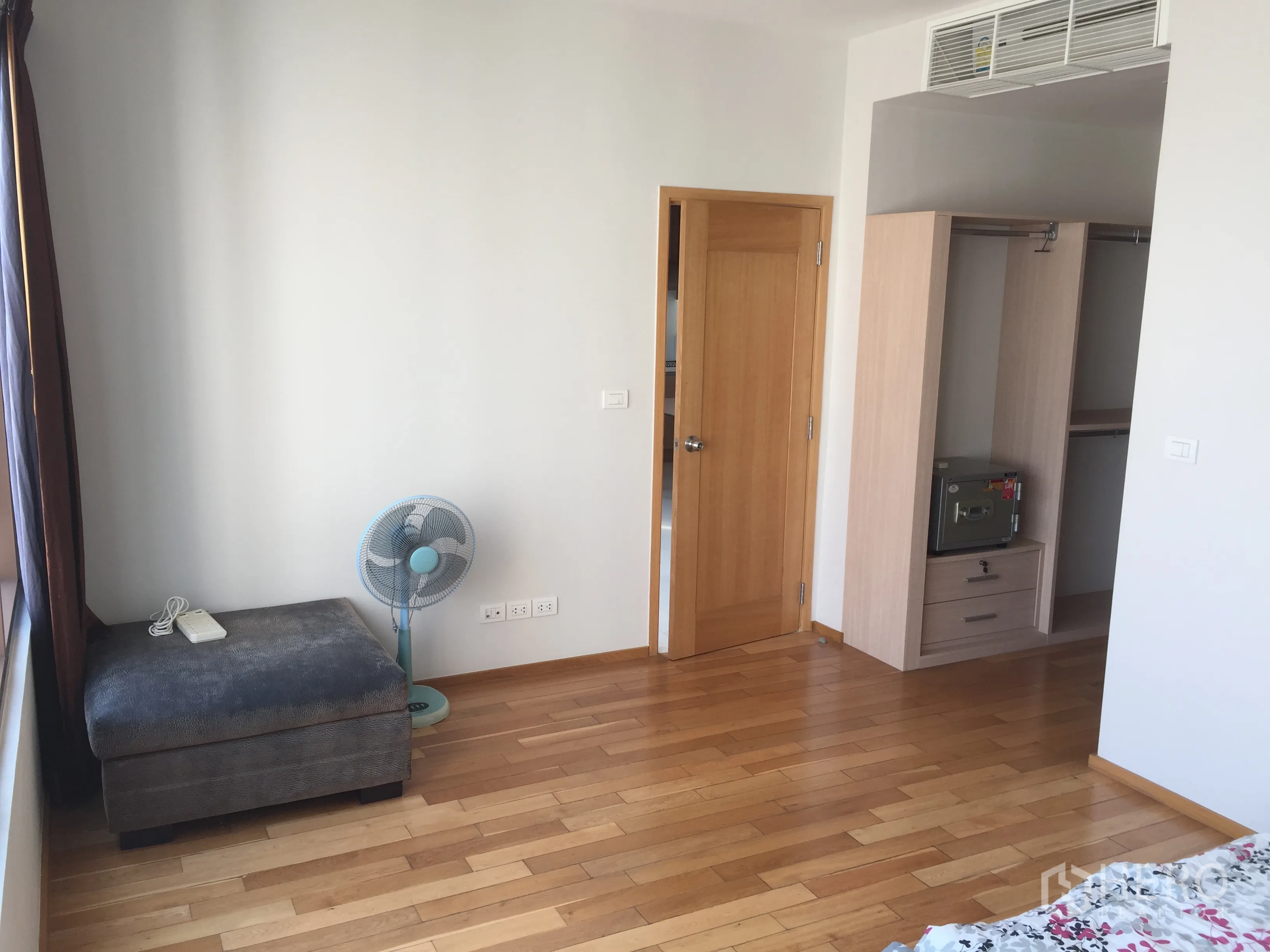 Condominium for rent or sale in Khlong Toei, Bangkok - Bright bedroom with hardwood floors, built-in wardrobe with safe and door to bathroom.