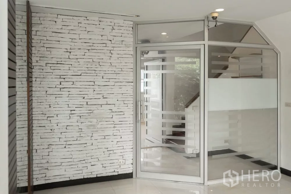 Home Office for rent in Lat Phrao, Bangkok - Glass-partitioned meeting room beside a white brick feature wall and stairs.