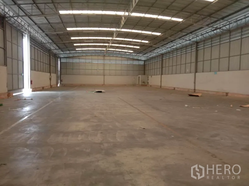 Warehouse for rent in Lat Krabang, Bangkok - Long view of empty warehouse hall featuring high ceiling, natural light strips and concrete slab.