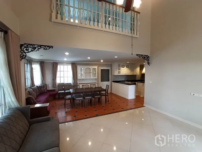 Detached House for rent in Mueang Samut Prakan, Samut Prakan - Open-plan living and dining space facing the kitchen, terracotta floors and mezzanine railing.