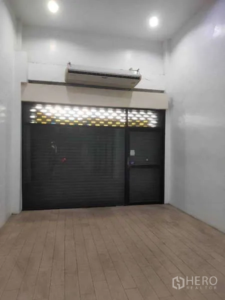 Shophouse for sale in Phra Khanong, Bangkok - Front roller shutter and glass entry beneath a high ceiling.