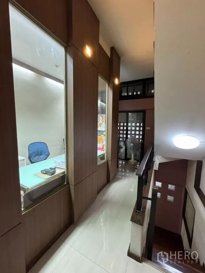 Shophouse for rent in Bang Rak, Bangkok - Upper-floor corridor with built-in glass display cabinets beside the staircase.