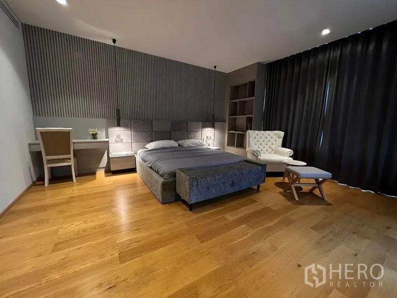 Detached House for sale in Suan Luang, Bangkok - Large bedroom with upholstered bed, armchair and warm wood floors.