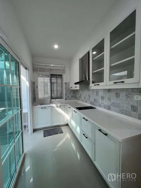 独立式住宅 出租或出售在Khan Na Yao, Bangkok - 现代一字型厨房，白色橱柜，炉灶与抽油烟机，推拉玻璃门。