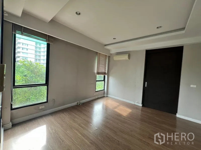 Townhouse for rent or sale in Khlong Toei, Bangkok - Corner room with wood floors, air conditioning and green views through large windows.