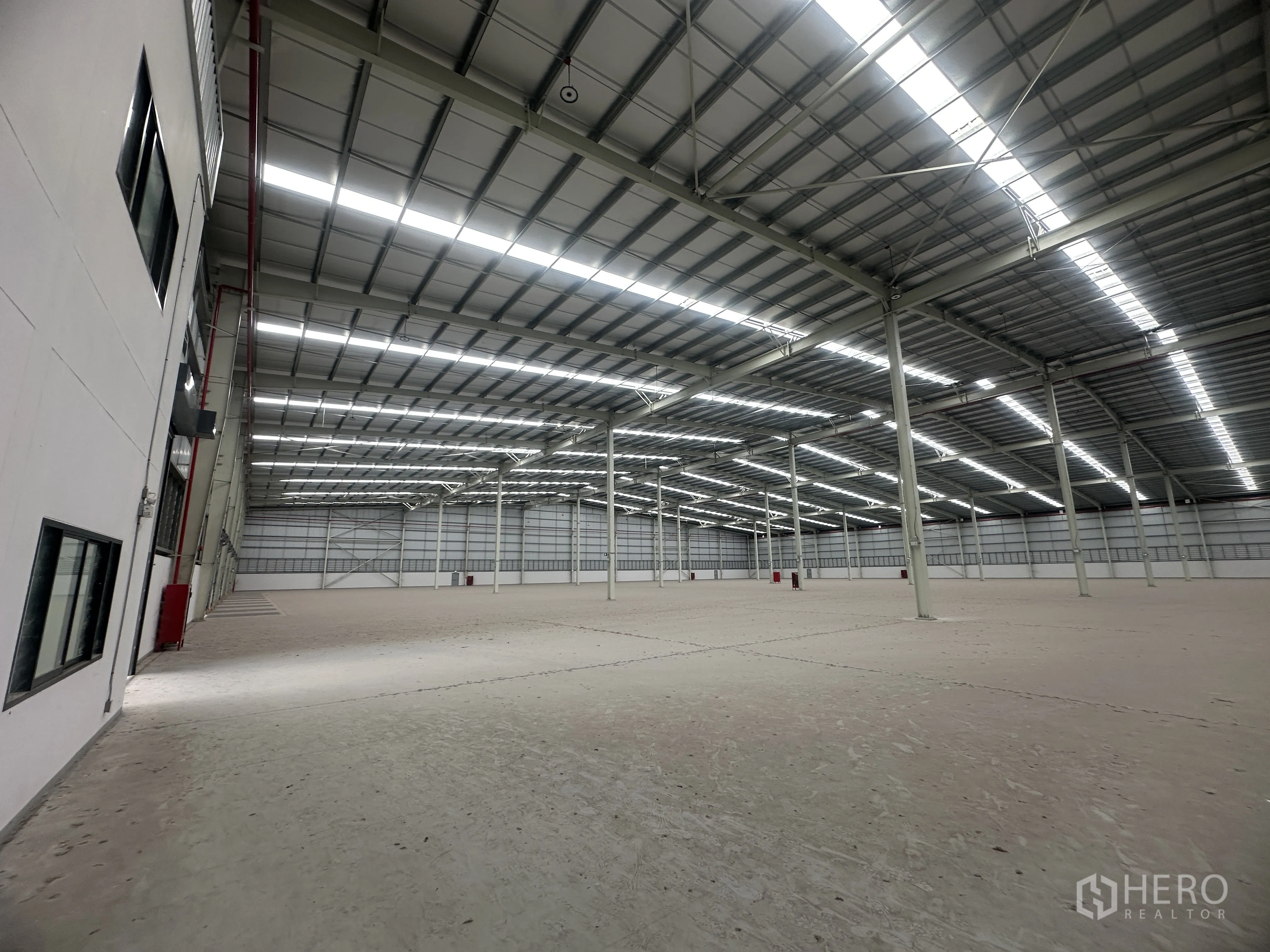 Warehouse for rent in Mueang Chon Buri, Chon Buri - Open storage floor with steel structure and safety equipment visible.