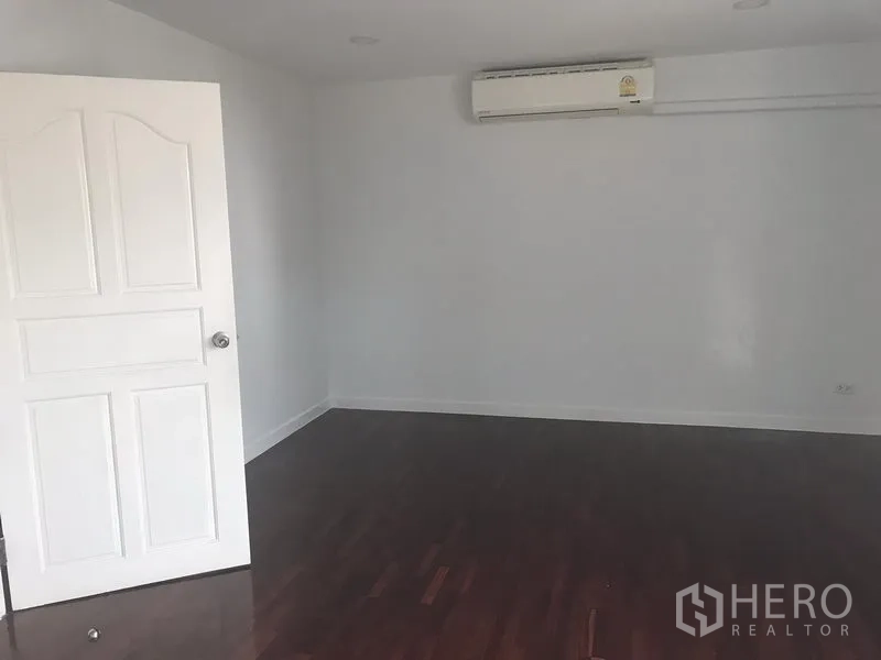 Home Office for rent or sale in Watthana, Bangkok - Clean office/bedroom with polished wood flooring, white door, and wall-mounted air-conditioner.