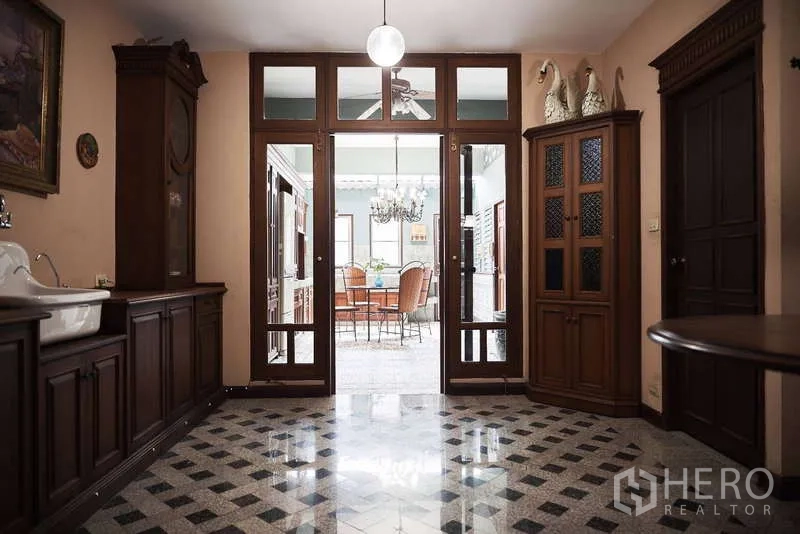 Townhouse for rent in Khlong Toei, Bangkok - Hallway view into kitchen through glass doors and wood cabinets
