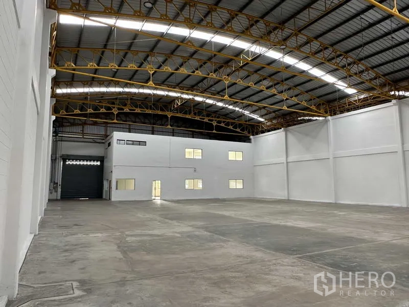 Factory for rent in Bang Phli, Samut Prakan - Warehouse interior showing roller shutter door and mezzanine-style office rooms.