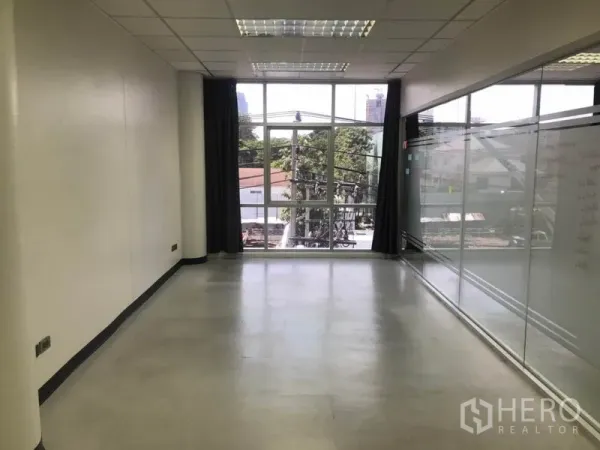 Office Space for rent in Khlong Toei, Bangkok - Long rectangular workspace facing a large window with a full glass partition opposite.