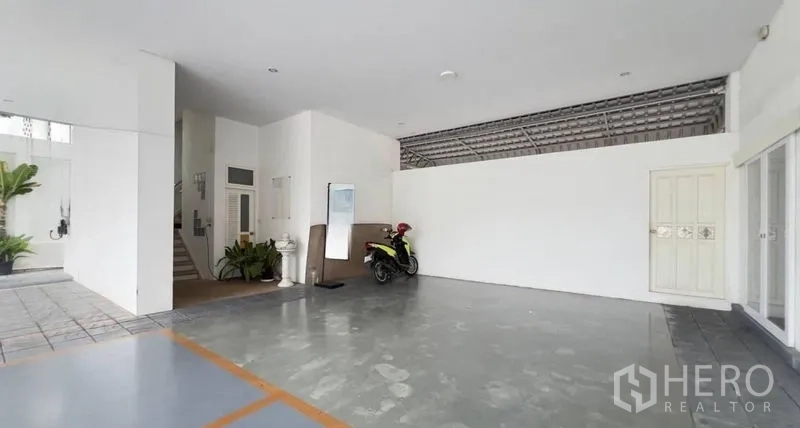 Standalone for rent in Khlong Toei, Bangkok - Spacious covered ground-floor parking and loading area with white walls.
