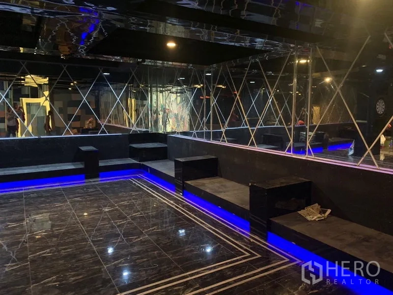 Shophouse for rent in Watthana, Bangkok - Mirrored lounge area with glossy black marble flooring, built-in benches, and blue LED accent lighting.