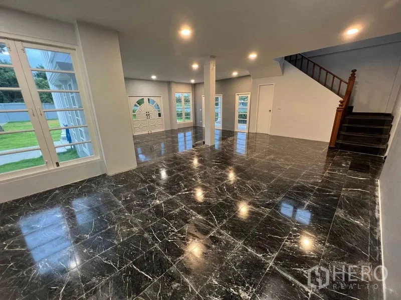 Detached House for sale in Bang Na, Bangkok - Grand living area with glossy black marble flooring and French doors to the garden.