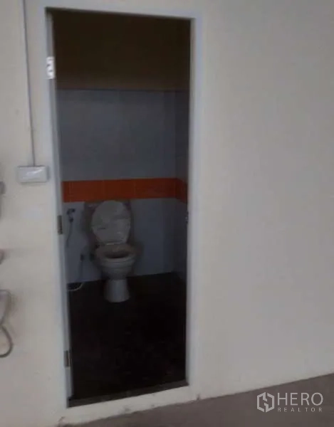 Factory for rent in Ban Phaeo, Samut Sakhon - Simple restroom with toilet and tiled walls inside the factory.
