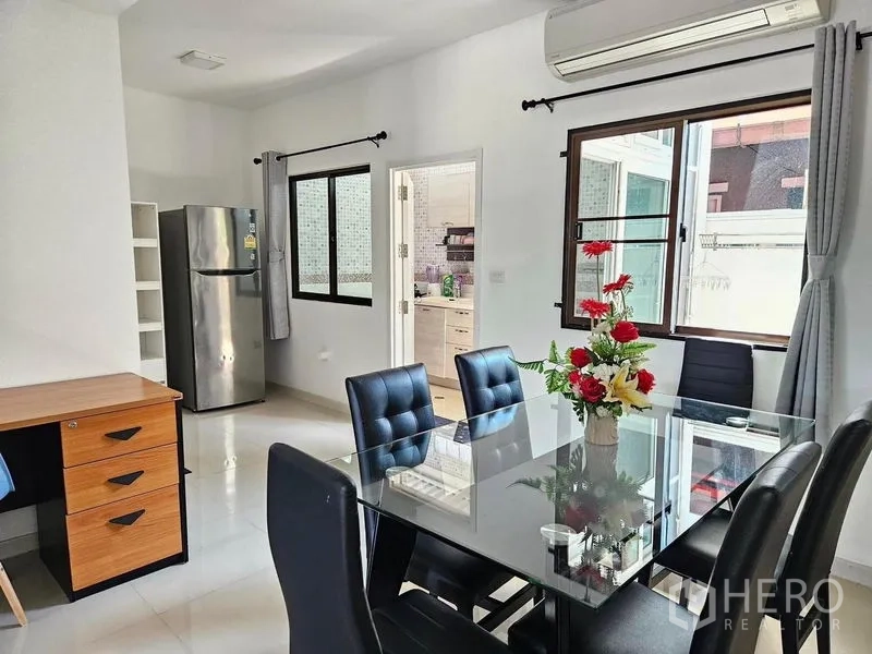 Townhouse for rent - Dining area with glass table, black chairs, wide windows, air conditioning and doorway to fitted kitchen.