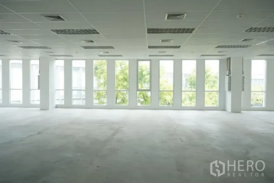 Office Space for rent in Bang Na, Bangkok - Bright empty open-plan office with floor-to-ceiling windows, suspended ceiling, lighting panels and air-conditioning vents.