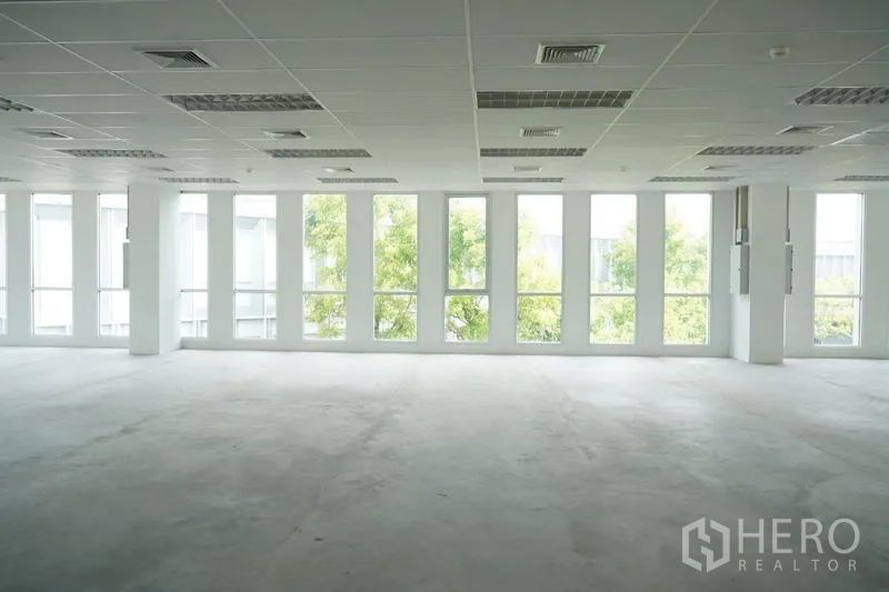 Office Space for rent in Bang Na, Bangkok - Bright empty open-plan office with floor-to-ceiling windows, suspended ceiling, lighting panels and air-conditioning vents.