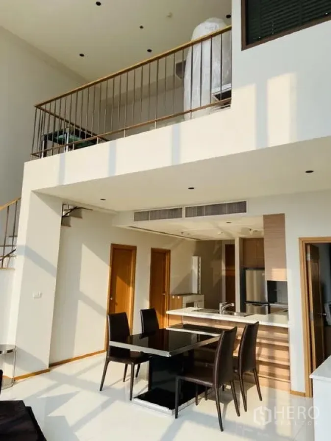 Condominium for rent in Khlong Toei, Bangkok - Double-height living space with mezzanine above and dining area below.