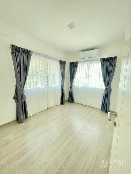 Townhouse for rent or sale in Prawet, Bangkok - Bright secondary bedroom with corner windows, sheers, blackout curtains and air conditioner.