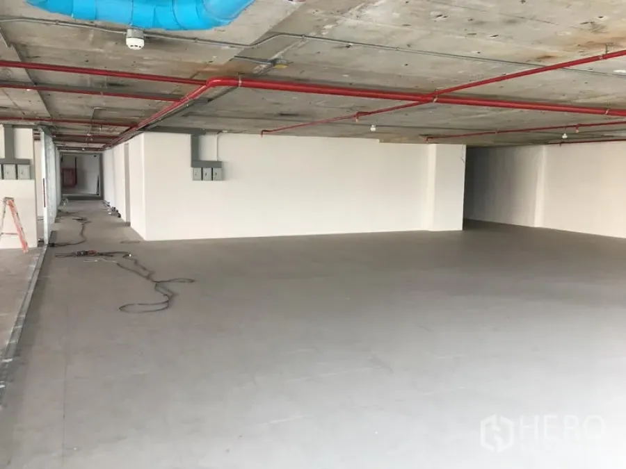Retail Space for rent in Khlong Toei, Bangkok - Open-plan retail unit with grey tiled floor, white walls, and exposed concrete ceiling with red fire pipes and blue ducting.