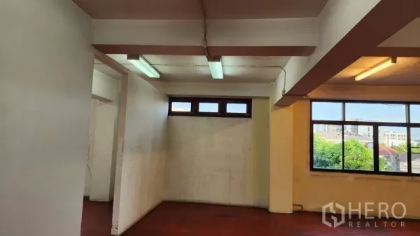 Office Space for rent or sale in Khlong Toei, Bangkok - Partitioned workspace with red flooring, fluorescent lighting, and exterior windows.