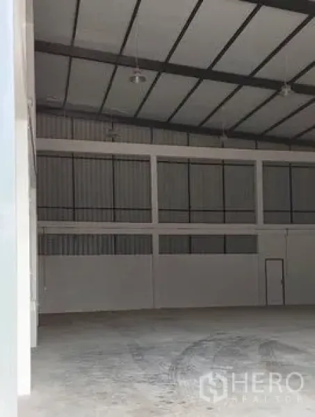 Warehouse for rent in Lam Luk Ka, Pathum Thani - Open-plan storage hall with concrete floor, tall roof trusses and wide wall sections.