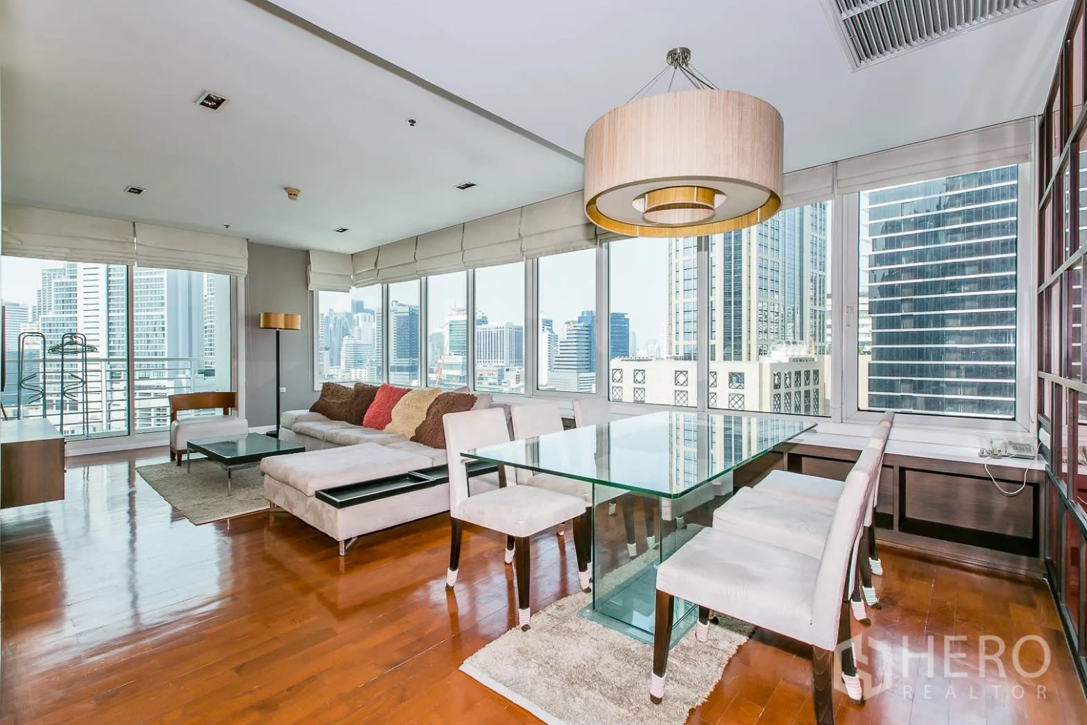 Condominium for rent or sale in Khlong Toei, Bangkok - Dining area with glass table beside corner windows overlooking the city.